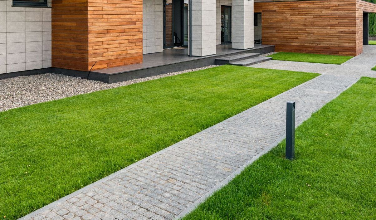 Exterior of contemporary residential house with green lawn and paths in sunny day